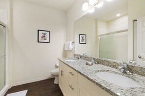 A bathroom with a double sink, a large mirror, and two framed pictures on the wall. - Villa CVX- Lucaya Village (Kissimmee)
