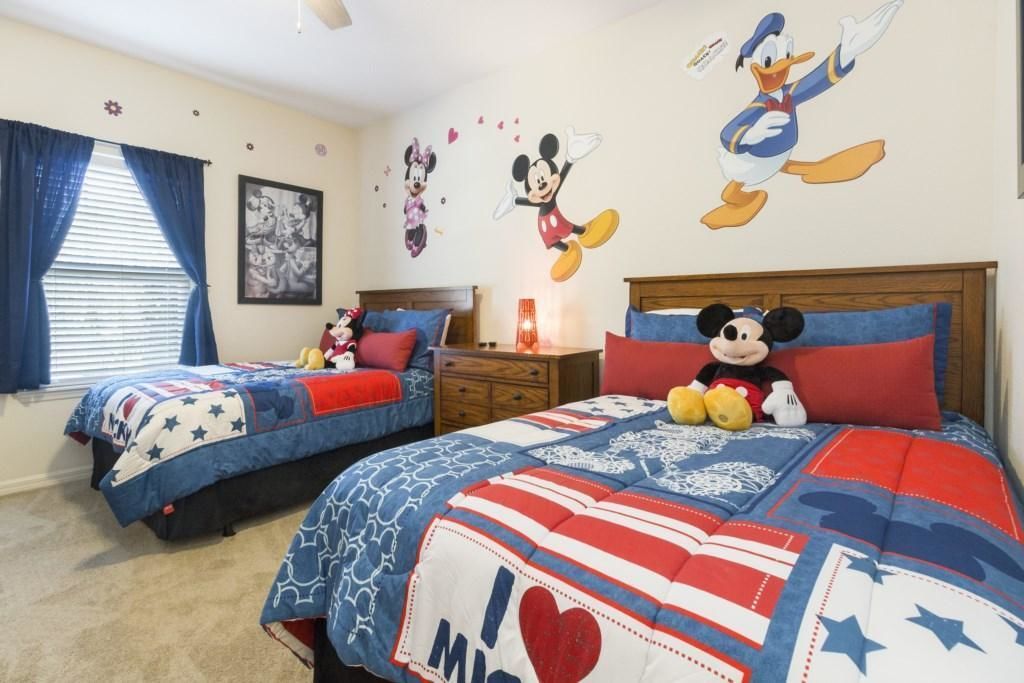 A bedroom with two beds, each with a Mickey Mouse-themed bedspread.