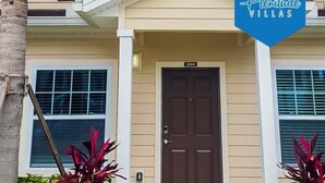 A two-story building with a beige facade, a brown door, and a number "3204" above the door. - Villa Guadalupe - West Lucaya (Kissimmee)