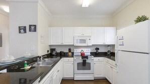 Una cocina con alacenas blancas, microondas, horno, pileta y refrigerador.