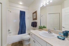 A bathroom with a bathtub, toilet, sink, and a large mirror.