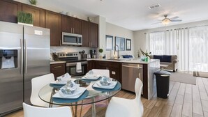 A modern kitchen with stainless steel appliances, a glass dining table, and a ceiling fan. - Villa Encantada - Windsor Palms (Kissimmee)