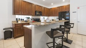 Eine moderne Küche mit Holzausstattung, einer zentralen Kochinsel mit Barhocker, einer Mikrowelle und einem Kühlschrank.
