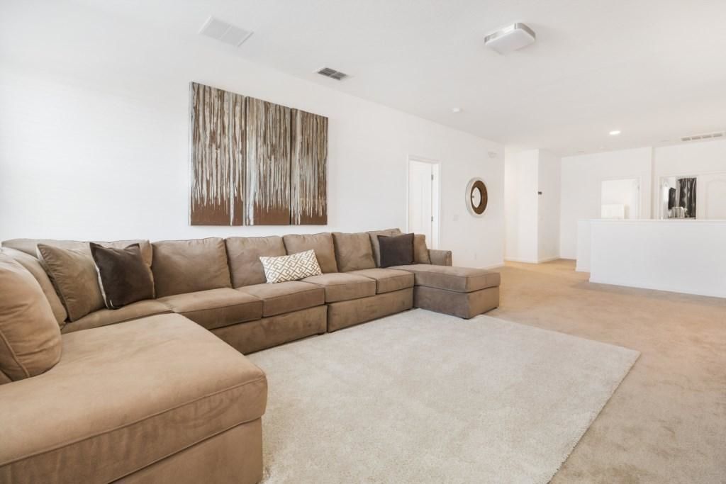 A living room with a large L-shaped sectional sofa, a neutral rug, and a minimalist decor.
