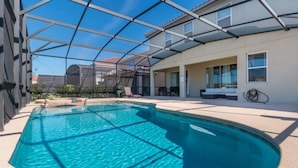 Ein Schwimmbecken mit Glasüberdachung, eine überdachte Terrasse und ein Gebäude mit zahlreichen Fenstern.