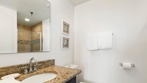 A bathroom with a granite countertop sink, a mirror, a toilet, and a towel rack. - Villa Yamagi - The Enclave Hotel & Suites (Orlando)
