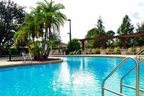 Ein Swimmingpool mit Palmen, Liegestühlen und einer Pergola.