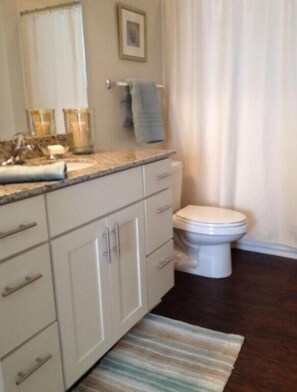 Ein Badezimmer mit Toilette, Waschbecken mit Spiegel und Handtuchhalter.