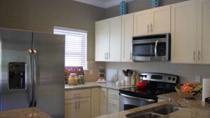 Uma cozinha moderna com eletrodomésticos de aço inoxidável, armários brancos e bancadas de granito.