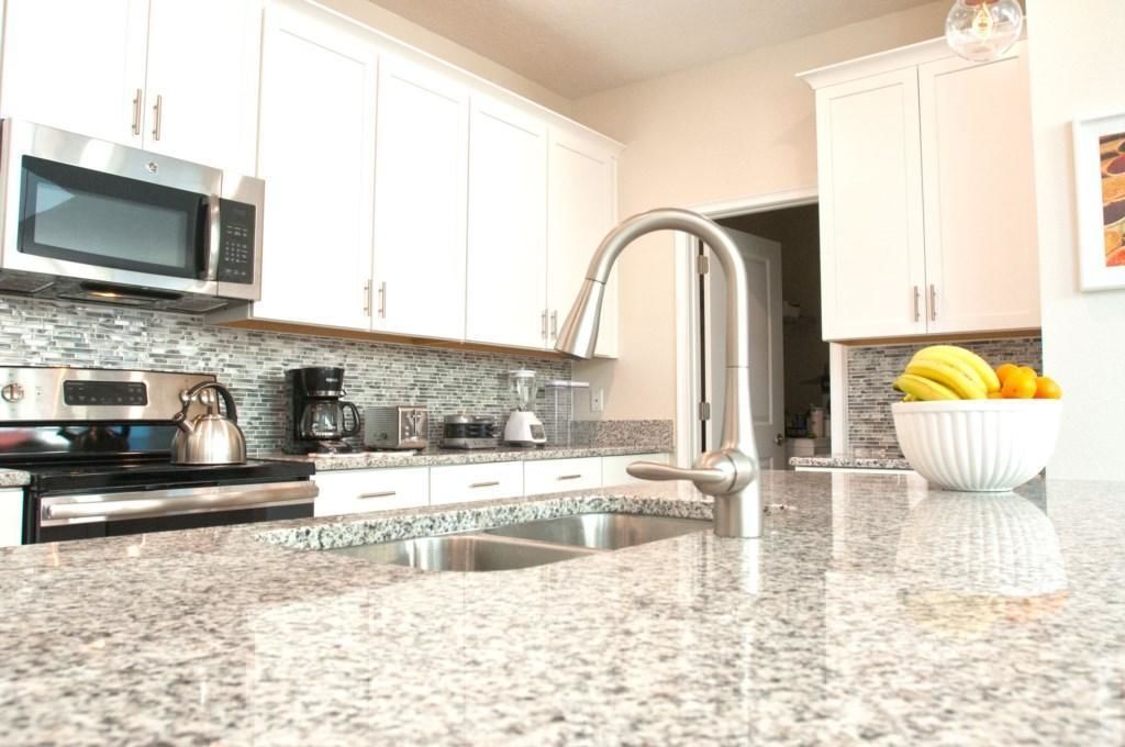 A modern kitchen with white cabinets, stainless steel appliances, and a granite countertop.