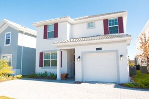 A two-story residential house with a white exterior, red shutters, and a garage. - Villa Sweet - Storey Lake (Kissimmee)