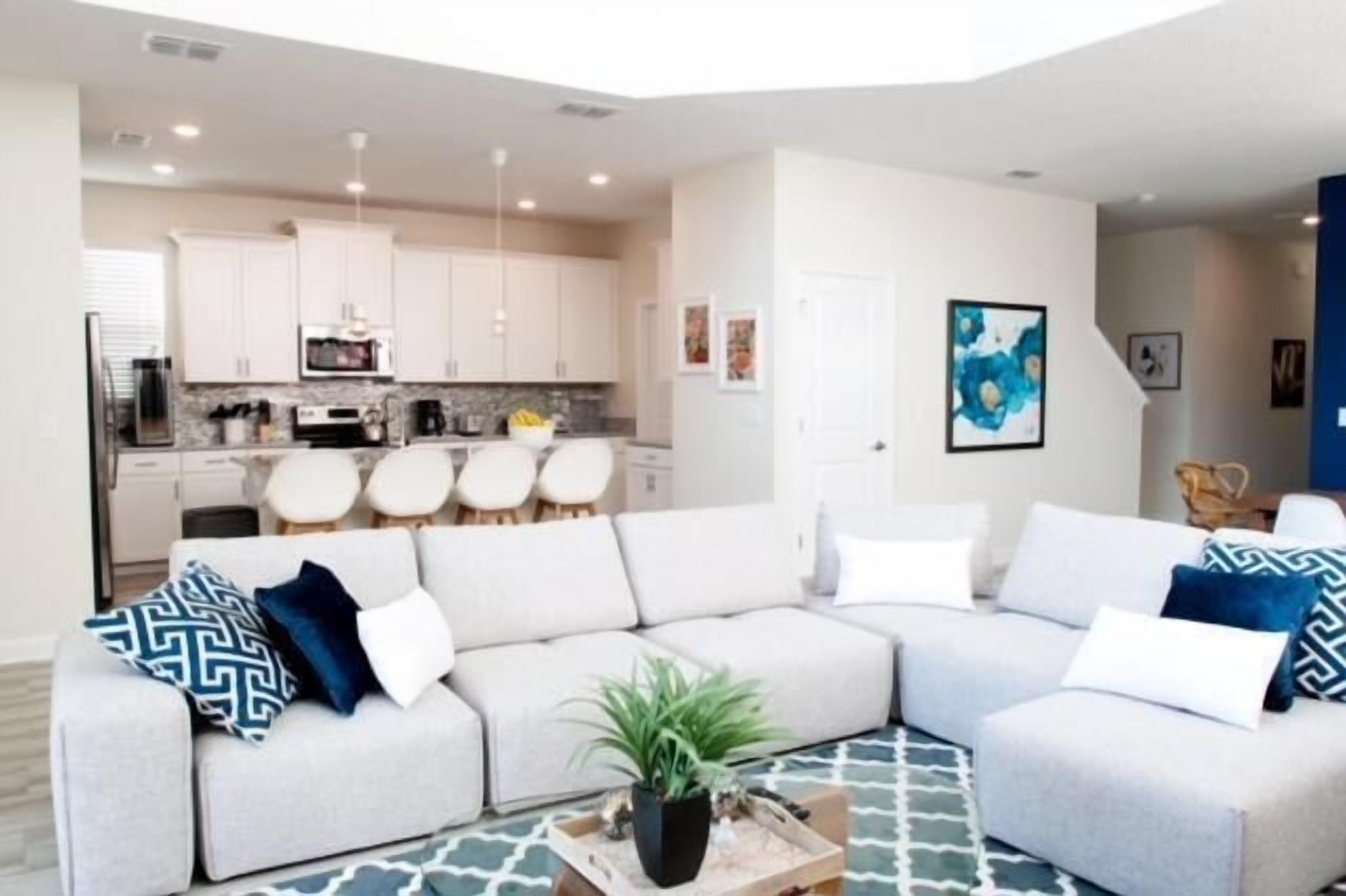 A modern living room with a sectional sofa, a coffee table, and a kitchen in the background.