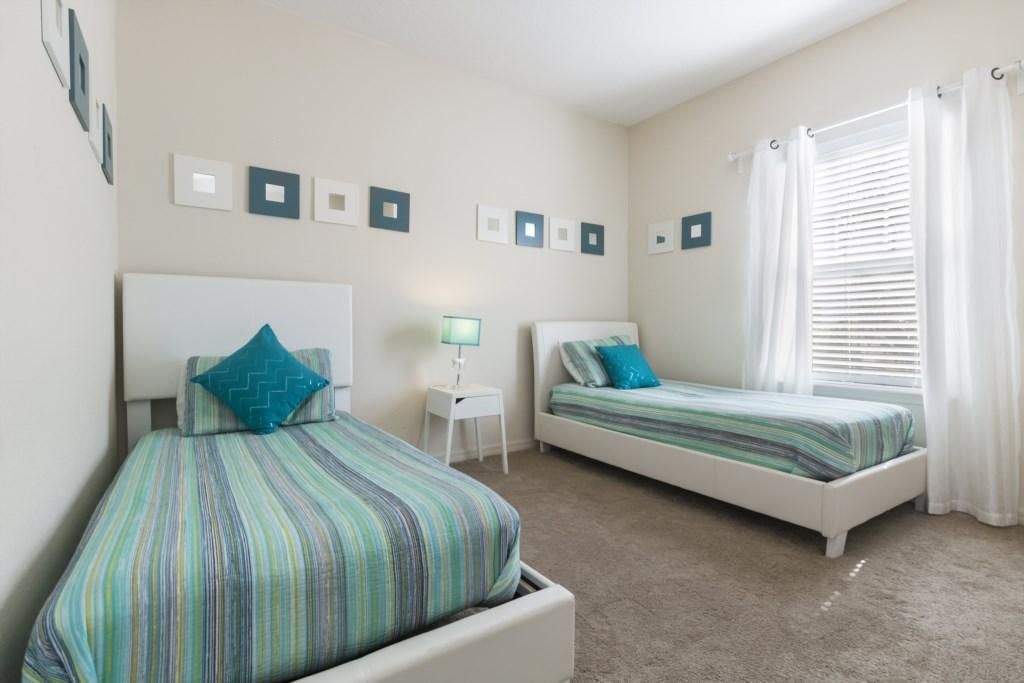 A bedroom with two beds, a nightstand, and a window with curtains.