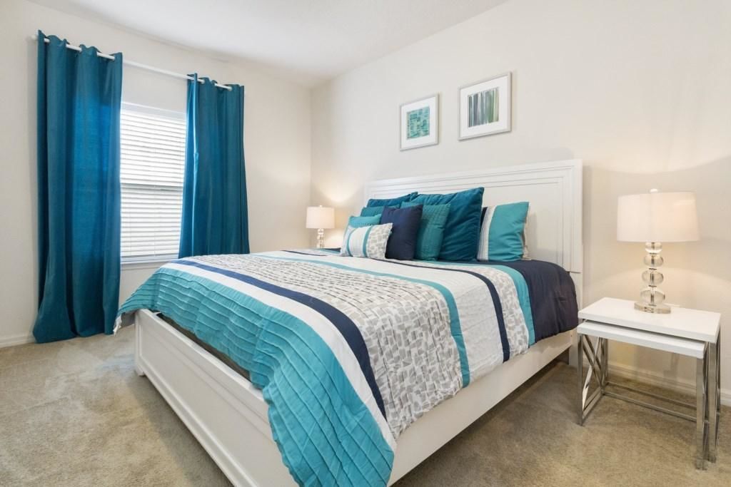 A bedroom with a bed, two bedside tables, and a window with curtains.