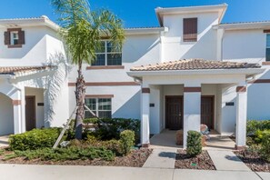A two-story building with a white facade, brown trim, and a tiled roof. - Villa Telles - Storey Lake (Kissimmee)