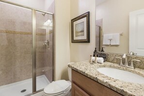 A bathroom with a glass shower enclosure, a sink with a granite countertop, and a framed picture on the wall. - Villa Telles - Storey Lake (Kissimmee)