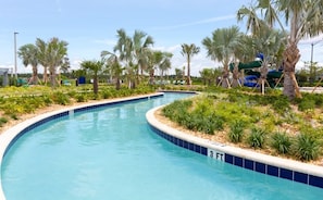 A swimming pool with a curved edge, surrounded by palm trees and greenery.