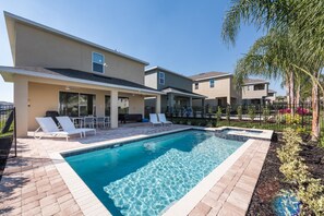 Área de piscina residencial com piscina limpa, espreguiçadeiras e um alpendre coberto.