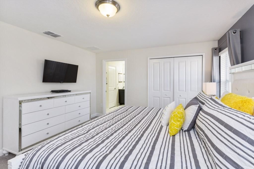 A bedroom with a bed, a dresser, a television, and a door.