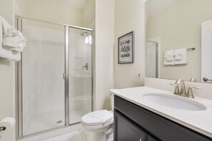 A modern bathroom with a glass shower enclosure, a white sink, and a mirror above the sink.
