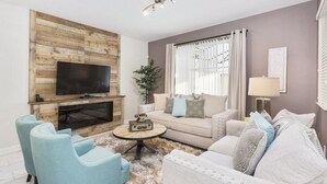 Ein modernes Wohnzimmer mit Flachbildfernseher, zwei Sofas, einem Couchtisch und einem Kamin.