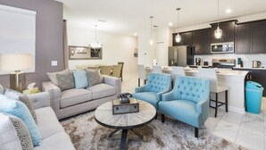 Ein modernes Wohnzimmer mit einem grauen Sofa, blauen Sesseln und einem Couchtisch.