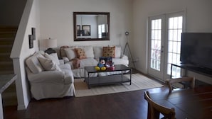 A living room with a sofa, coffee table, and a television.
