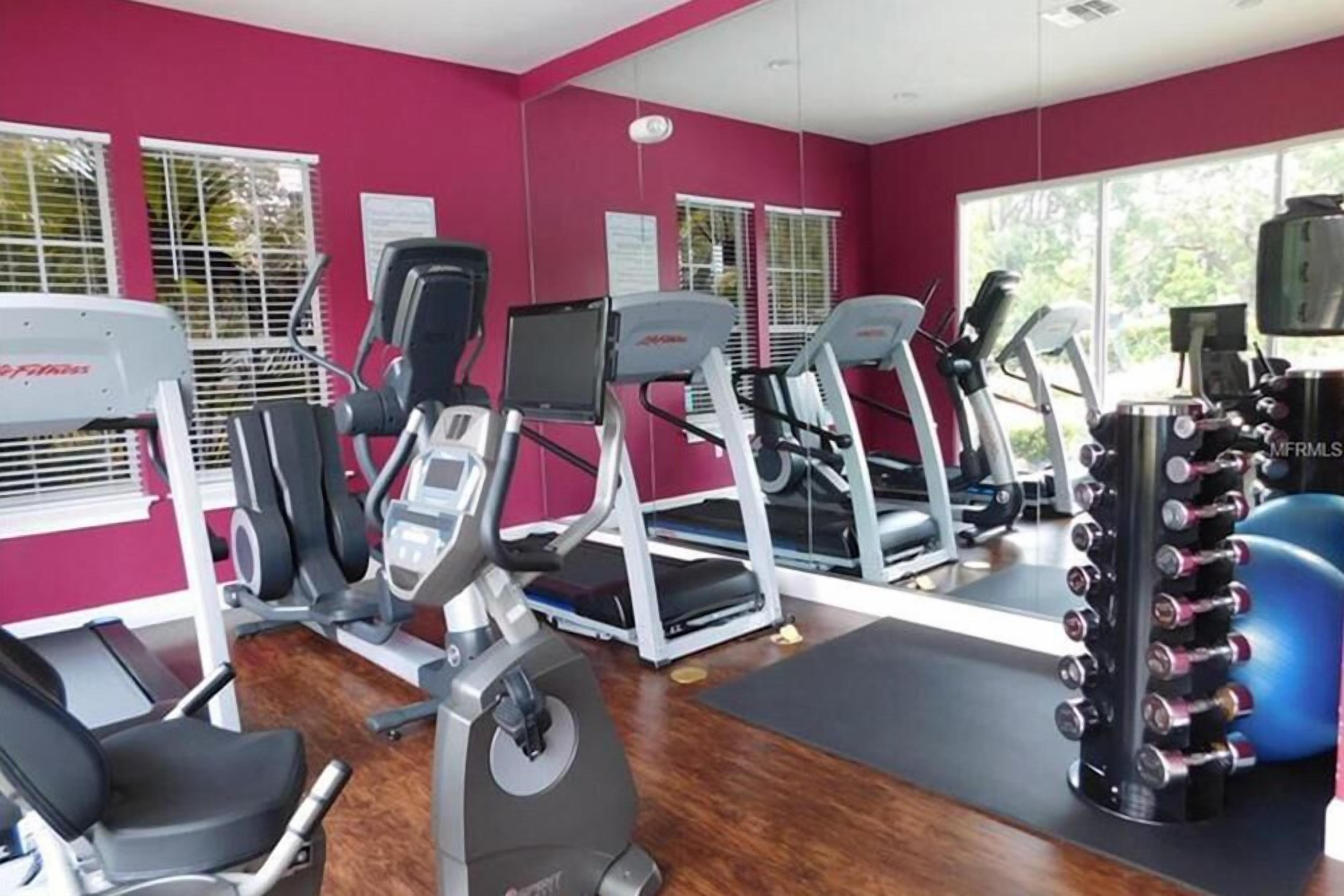 Un gimnasio con cintas de correr, elípticas y equipo de levantamiento de pesas.