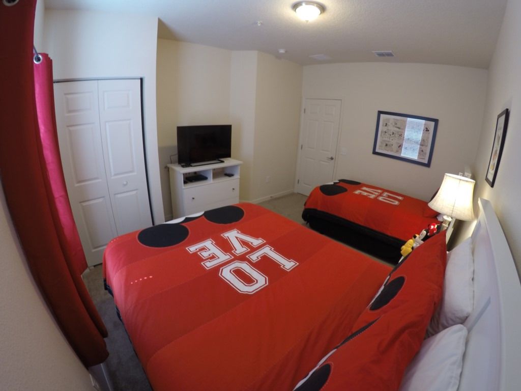 Quarto de hotel com duas camas, televisão, escrivaninha e porta.