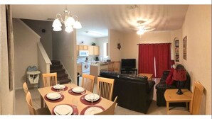 A dining area with a table set for four, a black leather sofa, and a television in the living room. - Villa Teixeira (Davenport)