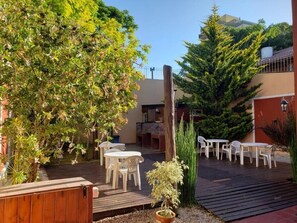 Eine Terrasse im Freien mit Holzbelag, weißen Plastikstühlen und Tischen.