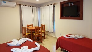 Une chambre d’hôtel équipée d’une table à manger, de deux lits, d’un téléviseur et d’un appareil de climatisation.