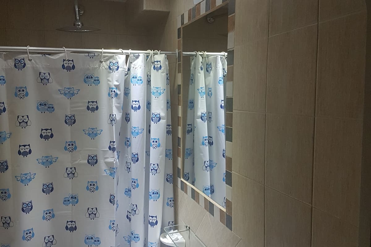 Une salle de bain avec un lavabo blanc, un miroir et un rideau de douche orné de motifs de hiboux.