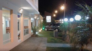 Un bâtiment doté d’un espace extérieur abrité, une voiture garée et un lampadaire.
