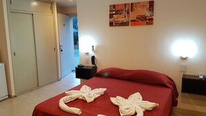 Une chambre d’hôtel avec un lit, un bureau, une chaise, une armoire et un tableau au mur.