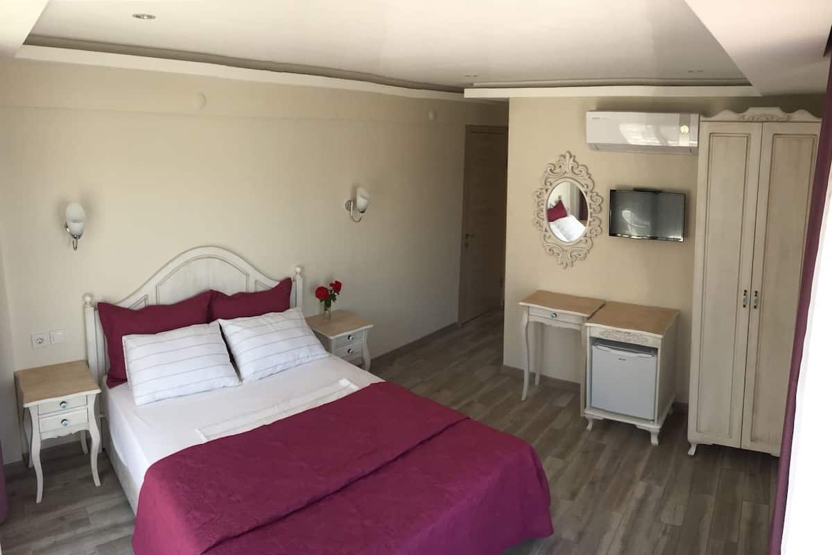 Ein Schlafzimmer mit einem Bett, Nachttischen, einem Schminktisch, einem Fernseher und einer Klimaanlage.