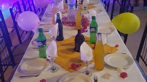 A long dining table set outdoors with balloons, bottles, and plates. - Auberge Etoile Mirleft (Mirleft)