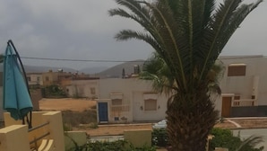 A table set for two with a view of a swimming pool and buildings in the background. - Auberge Etoile Mirleft (Mirleft)
