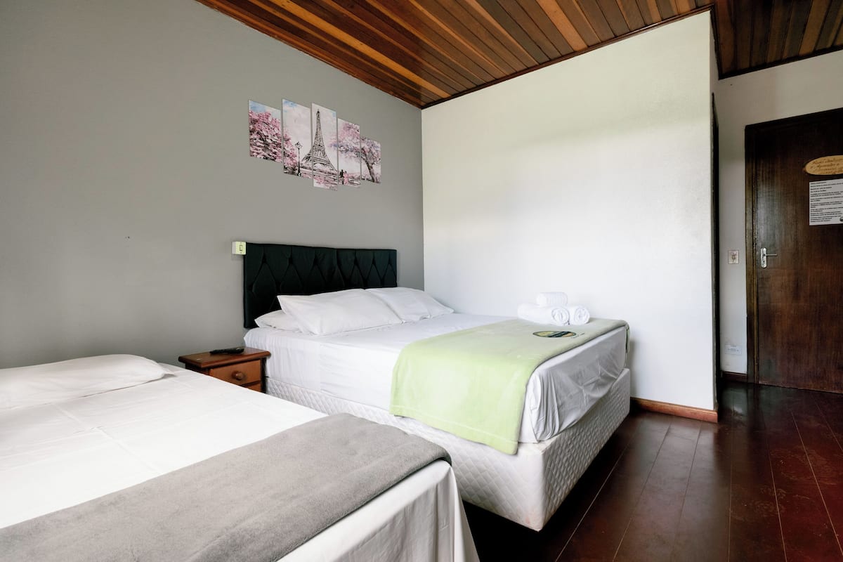 Ein Hotelzimmer mit zwei Betten, einer Holzbalkendecke und einer Wand mit einem Bild vom Eiffelturm.