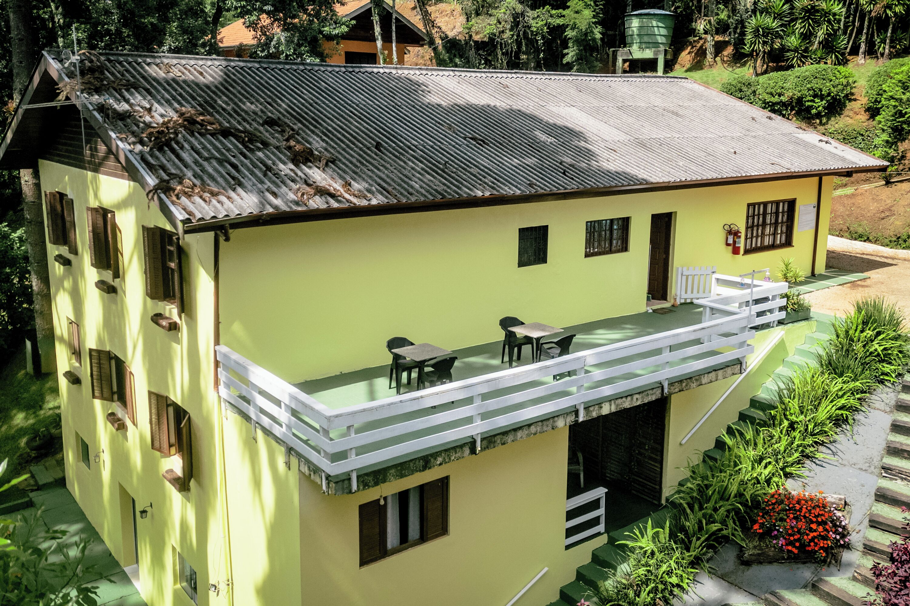 A yellow building with a balcony, a staircase, and a small garden area.