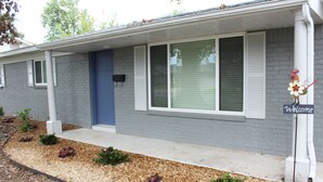Une maison d'habitation avec une porte bleue, des volets blancs et une pancarte indiquant « Bienvenue ».