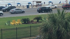 Ein Parkplatz am Strand mit Autos, Strandsonnenschirmen und Blick auf den Ozean.