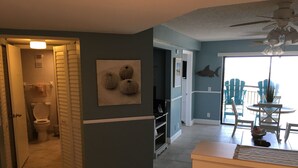 Uma sala de estar com área de jantar, ventilador de teto e vista para o exterior.