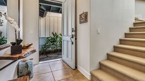 Una escalera con peldaños alfombrados en color beige que conducen a una puerta con marco blanco.