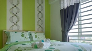 A neatly made bed with green leaf-patterned bedding, a headboard, and pillows with leaf designs. - H&A HOMESTAY Comfortable and Convenient for touring around Ipoh. (Taman Jubilee)