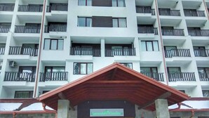 Un edificio de varios pisos con una entrada de techo rojo identificada como 'Borovets Gardens'.