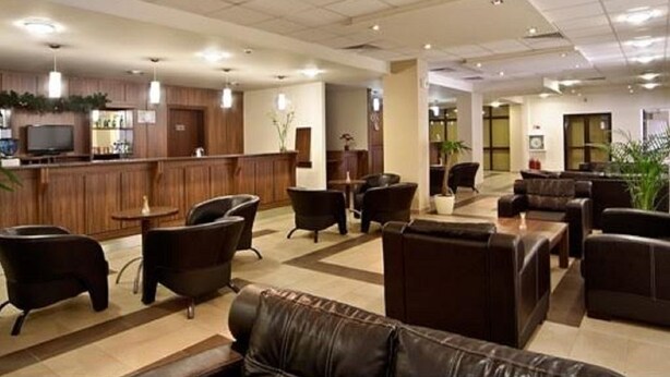 Un hall de hotel con sofás de cuero, un mostrador de recepción y una zona de bar.