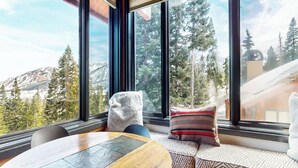 A room with a large window, a wooden table, and a bench with cushions. - Remodeled Home, Amazing Views, Private Hot Tub & Garage, Near the Lakes Basin (Mammoth Lakes)