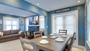 A dining area with a wooden table set for six, a fireplace, and a television on the wall. - Conesus Lake Front Retreat (Conesus)