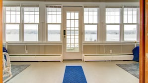 A room with a large window, a door, and a blue rug. - Conesus Lake Front Retreat (Conesus)